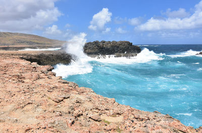 Large wave crashing against the rock bluffs in aruba.