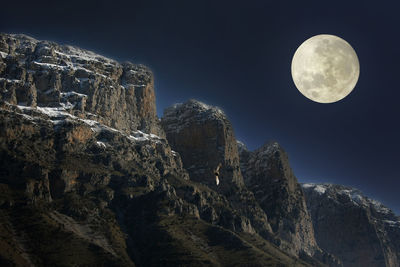 Full moon over mountains against clear sky at night