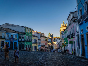 Illuminated city street against blue sky