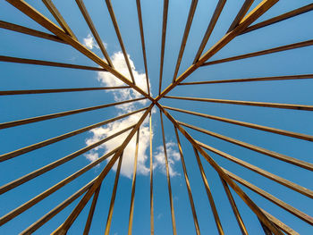 Wooden structure seen from below, with blue sky and small clouds on top.