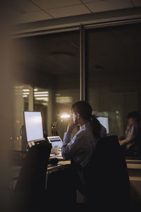 Young businesswoman working on computer late night in office