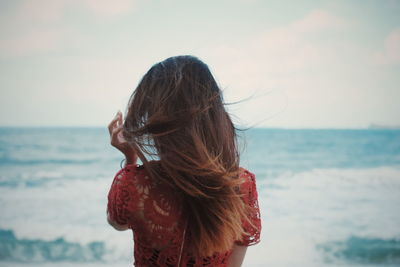 Rear view of woman at beach against sky