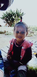 Portrait of smiling girl sitting outdoors
