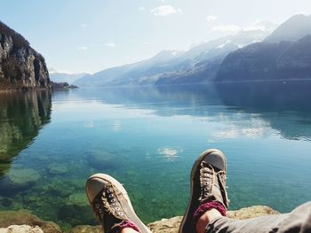 Low section of person on lake against mountains