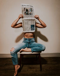 Full length of woman sitting on chair at home