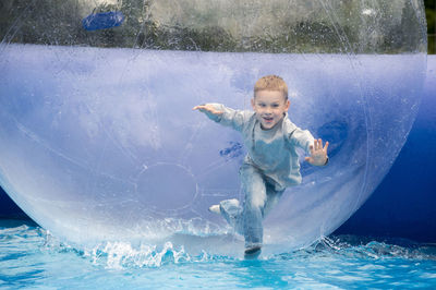 Cheerful boy in water walking ball on swimming pool