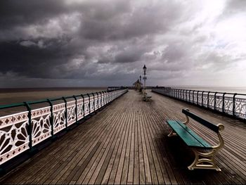 Pier on sea against cloudy sky