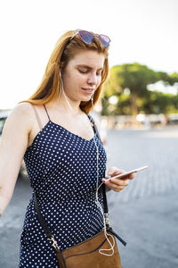 Glad female in earphones using smartphone