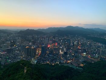 High angle view of illuminated city against sky during sunset