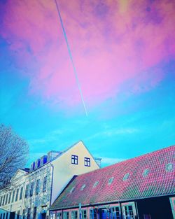 Low angle view of rainbow over building against sky