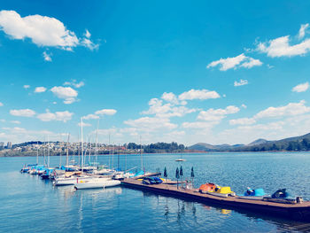 Sailboats moored in sea against sky