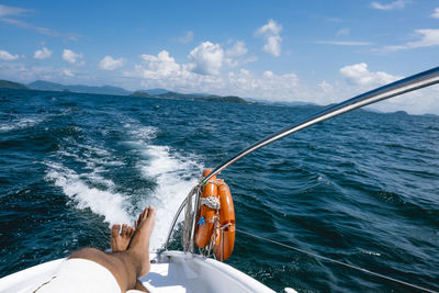 Low section of man sailing on sea against sky