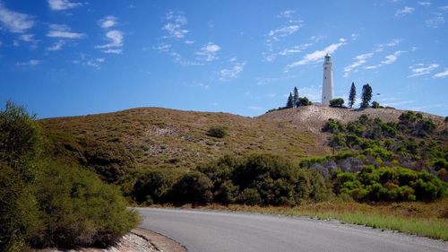 Road by lighthouse on hill against sky