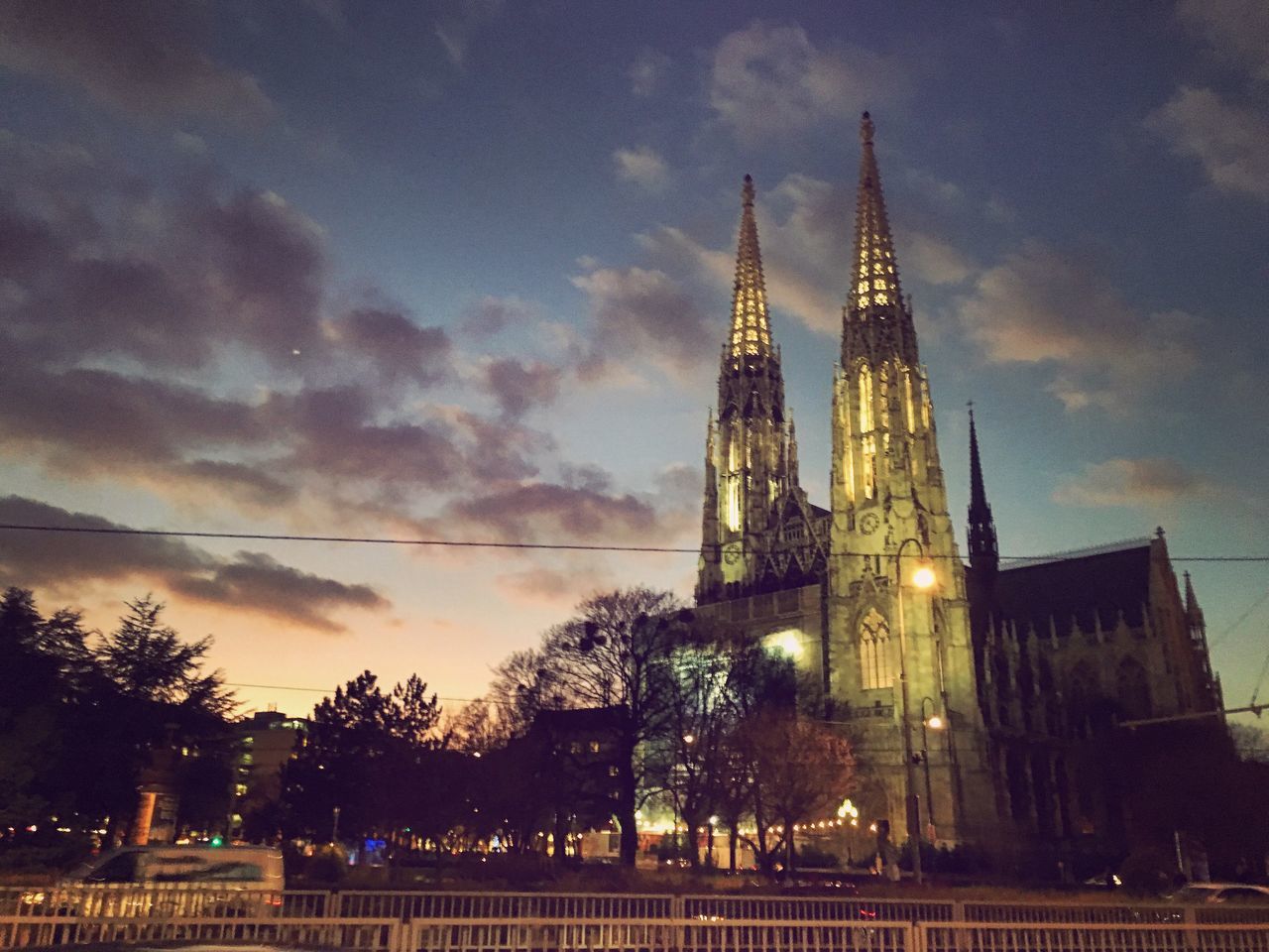 architecture, built structure, building exterior, sky, low angle view, cloud - sky, place of worship, tree, religion, illuminated, tower, dusk, spirituality, church, cloud, cloudy, city, famous place, outdoors