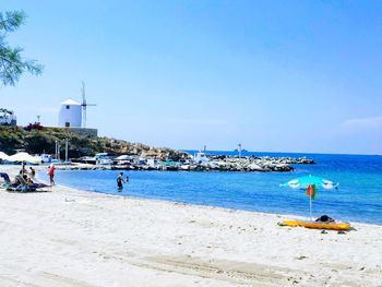 People on beach against clear sky