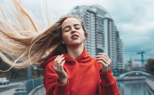 Young woman tossing hair while standing in city