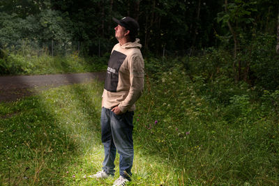 Full length of man standing by plants while looking up outdoors