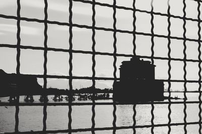 Silhouette chainlink fence against sky