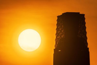 Low angle view of silhouette built structure against orange sky