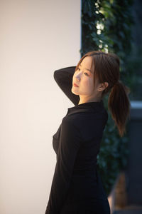 Young woman looking away against wall