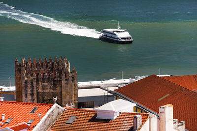 Rooftops against boat in blue sea