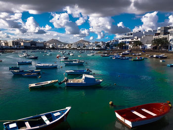 Sailboats moored in sea against blue sky