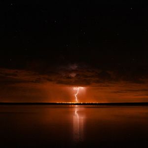 Scenic view of sea against sky at night wirh lightning 