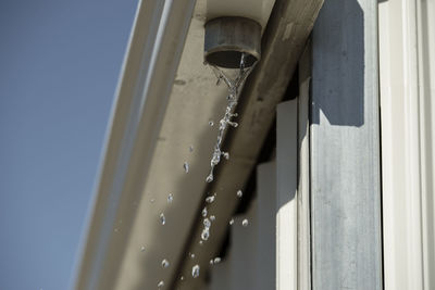 Low angle view of water dripping from broken gutter 