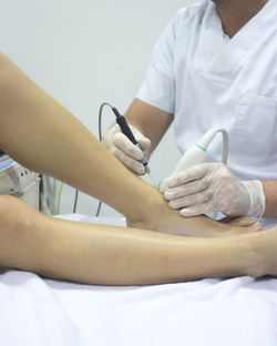 Midsection of doctor holding monitoring equipment and syringe on patient