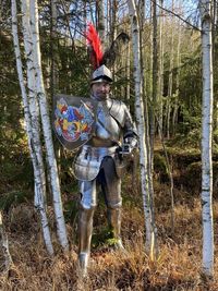 Full length of warrior standing by trees in forest