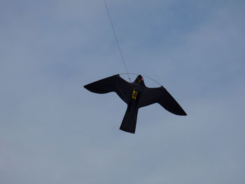 Low angle view of bird shape kite flying in sky