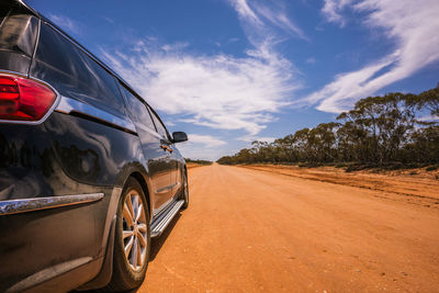 Car on dirt road against sky