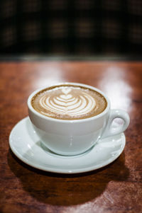 Close-up of cappuccino in white cup on wooden table