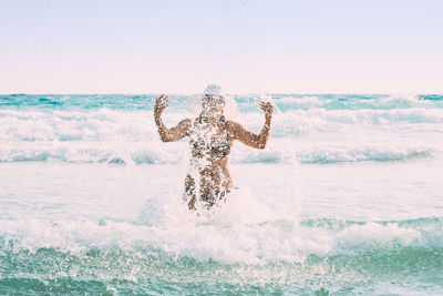 Rear view of woman with arms outstretched standing on snow