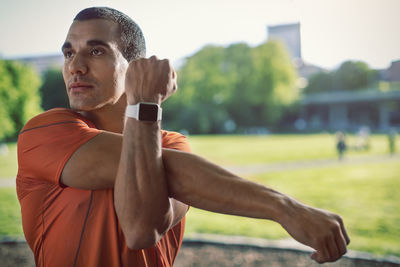 Man wearing wristwatch stretching arm at park