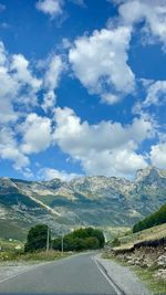 Road by mountains against sky