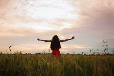 Woman standing on field against sky during sunset