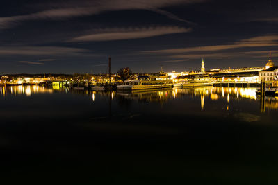 Scenic view of lake by illuminated city at night