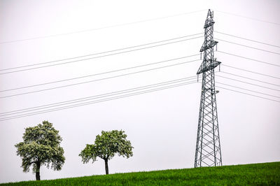 Low angle view of electricity pylon on field