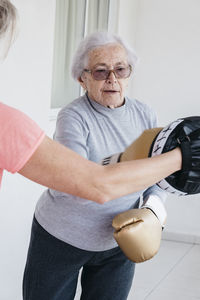 Senior woman boxing with fitness instructor