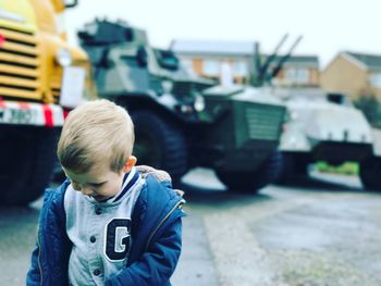 Boy looking down while standing on street