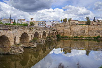 Arch bridge over river against cloudy sky