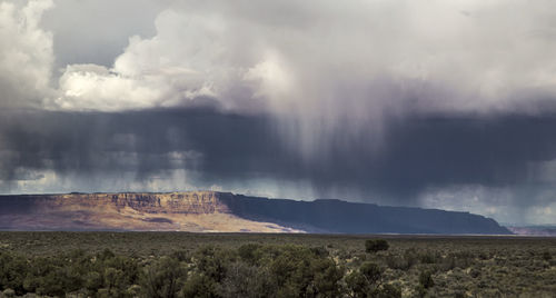 Scenic view of desert under stormy clouds