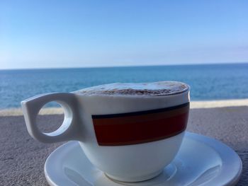 Close-up of coffee on table by sea against sky