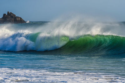 Waves splashing on sea against sky