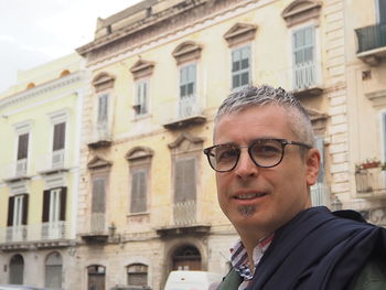 Portrait of man standing by building in city