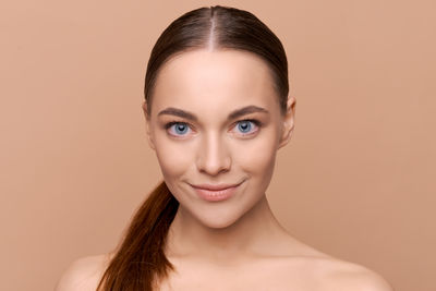 Close-up portrait of young woman against pink background