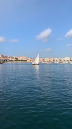 Sea by buildings against blue sky