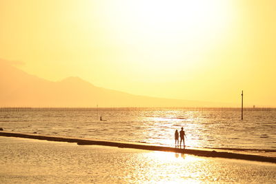 Silhouette person on beach against sky during sunset