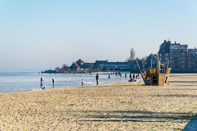 People on beach against clear sky